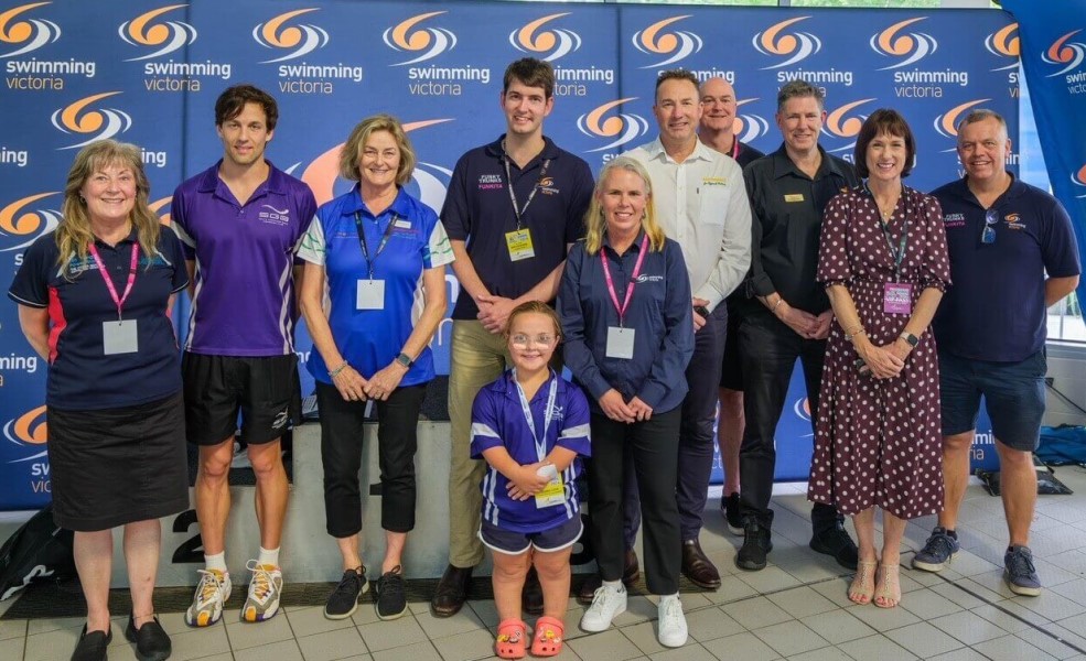 A group of 11 representatives from Swimming Victoria of varying ages, including Michelle Harris standing in the middle of the group 