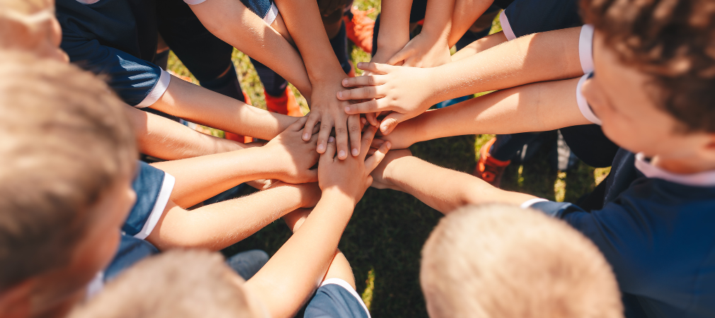 Group of young kids with hands in the middle of a huddle 